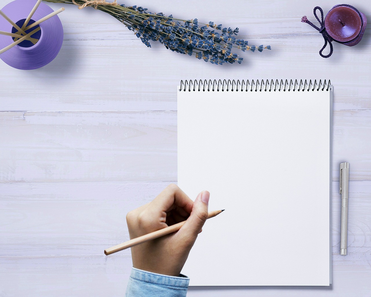 A person holding a pen above a blank page.
